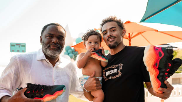 Trae Young alongside his father and son hold black and red adidas shoes.